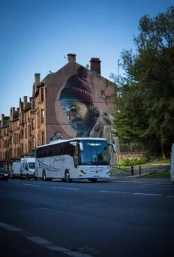 Hire Society Coach by The Saint Mungo Mural in Glasgow