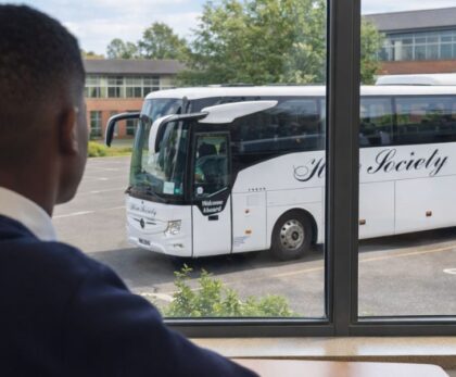 School bus hire Glasgow – pupil looks at a modern Hire Society coach outside his school in Glasgow