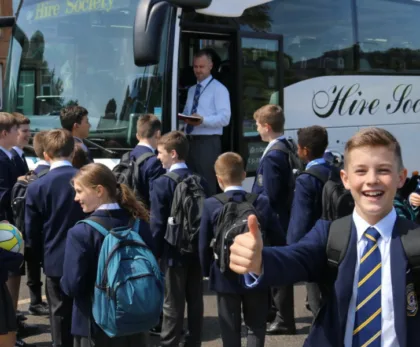 A school group boarding a coach with backpacks and sports kit. Coach hire for school trips and sports tours Scotland, safe group transport for pupils